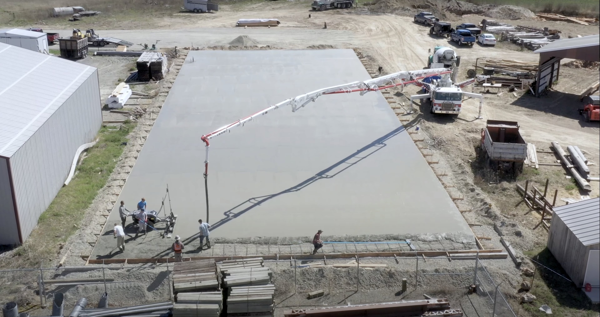 Large-scale commercial concrete slab installation with concrete pump truck and professional crew